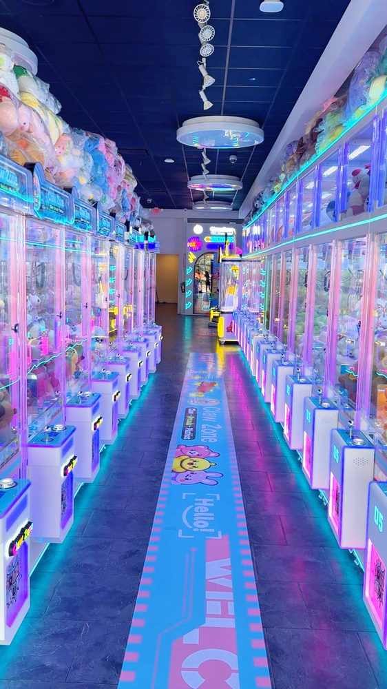 Neon-lit aisle of claw machines at Claw Zone