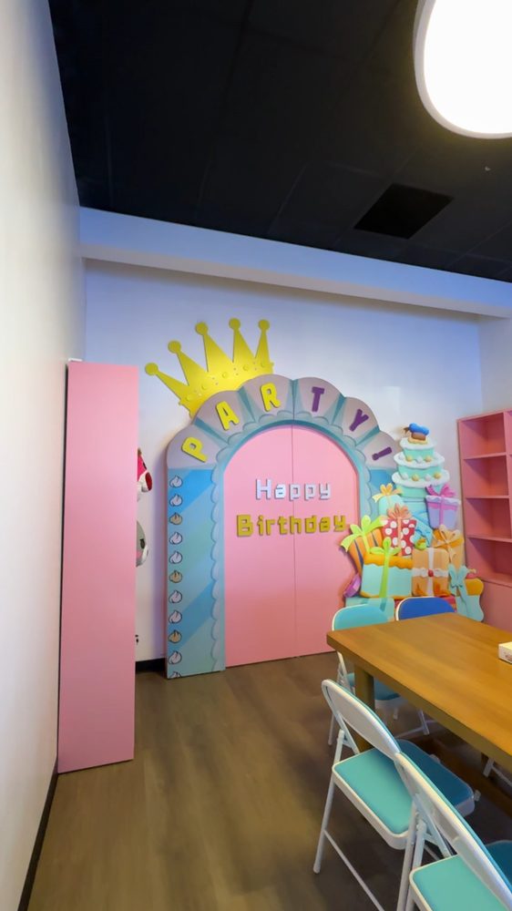 Claw Zone pink birthday party room with a Happy Birthday backdrop and table seating